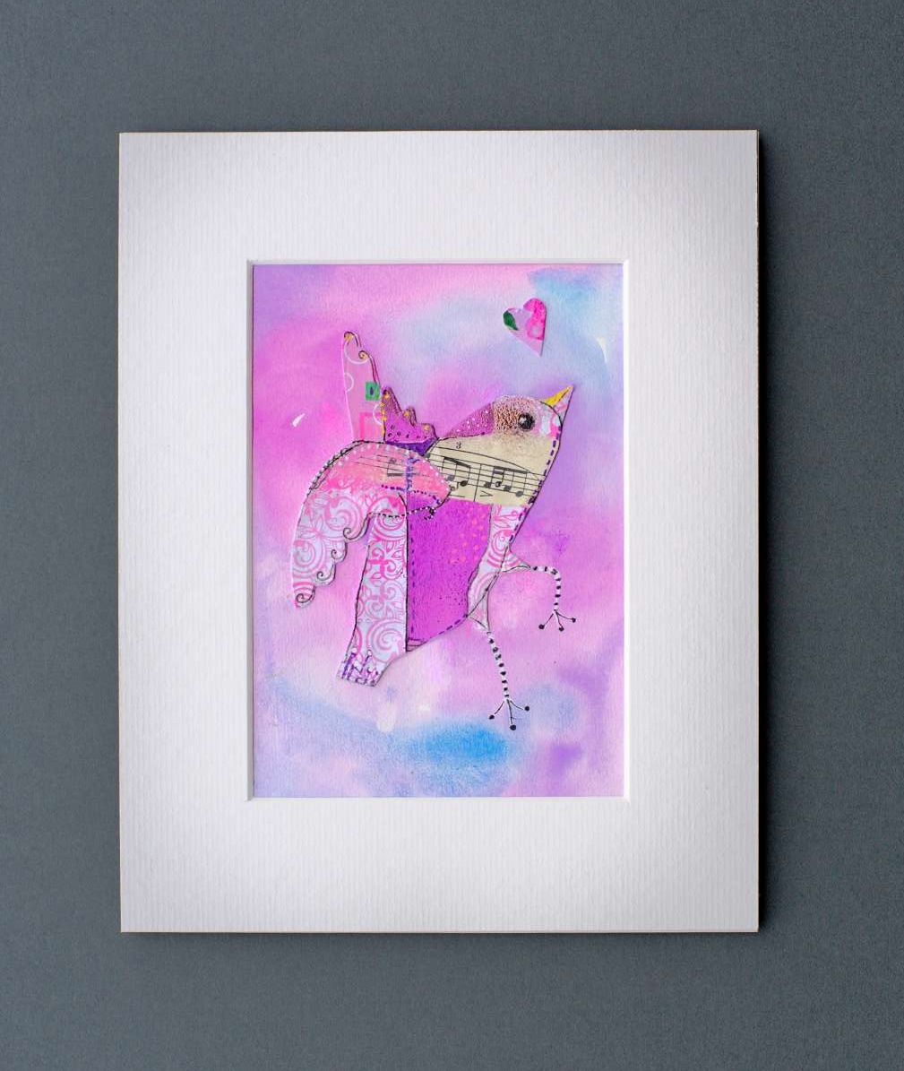 funky bird art - collage bird made from assorted pink papers and sheet music on a pink and blue cloudy watercolour background