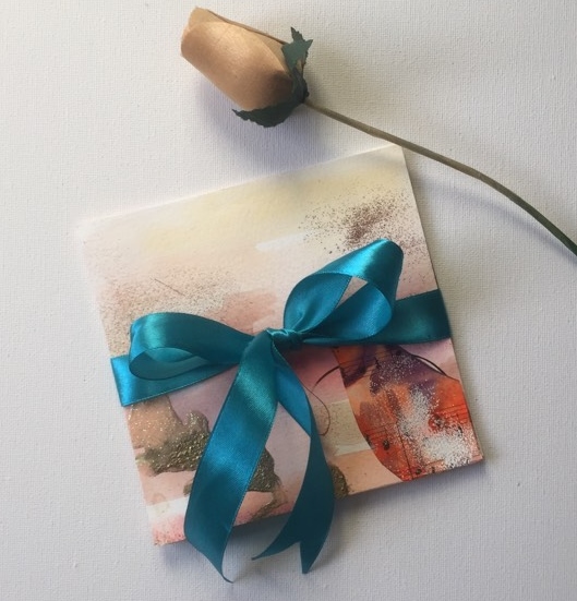 Bundle of three pieces of art related to meditation. Wrapped up in a blue ribbon beside a wooden rose