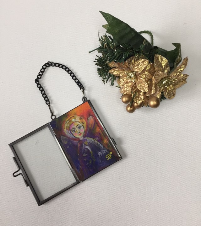 Special Christmas Angel - hanging decoration. The angel is painted with orange, gold and purple tones. She is encased in a glass frame that can hang on your Christmas tree or on the wall.