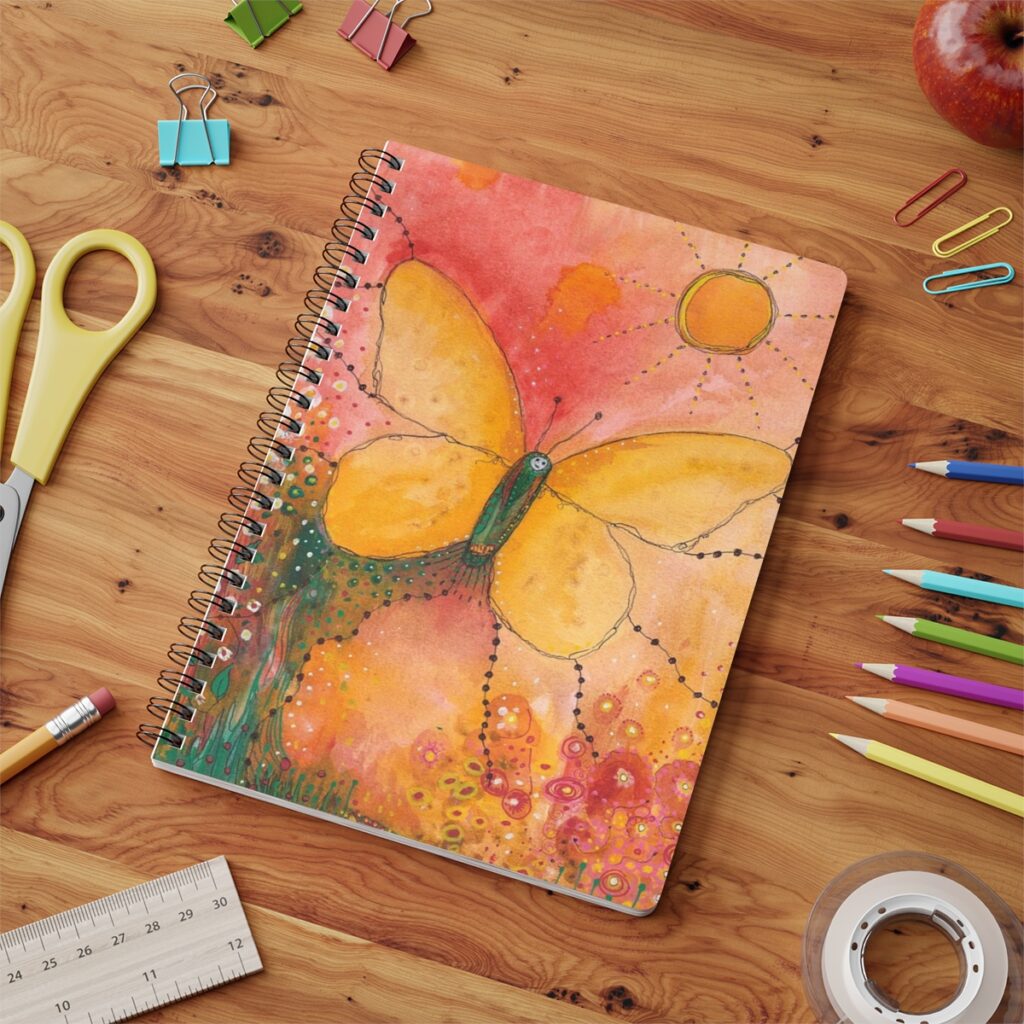 Butter fly notebook in context. Image of butterfly uses soft tones of yellows and oranges and the butterfly is rising to greet the sun