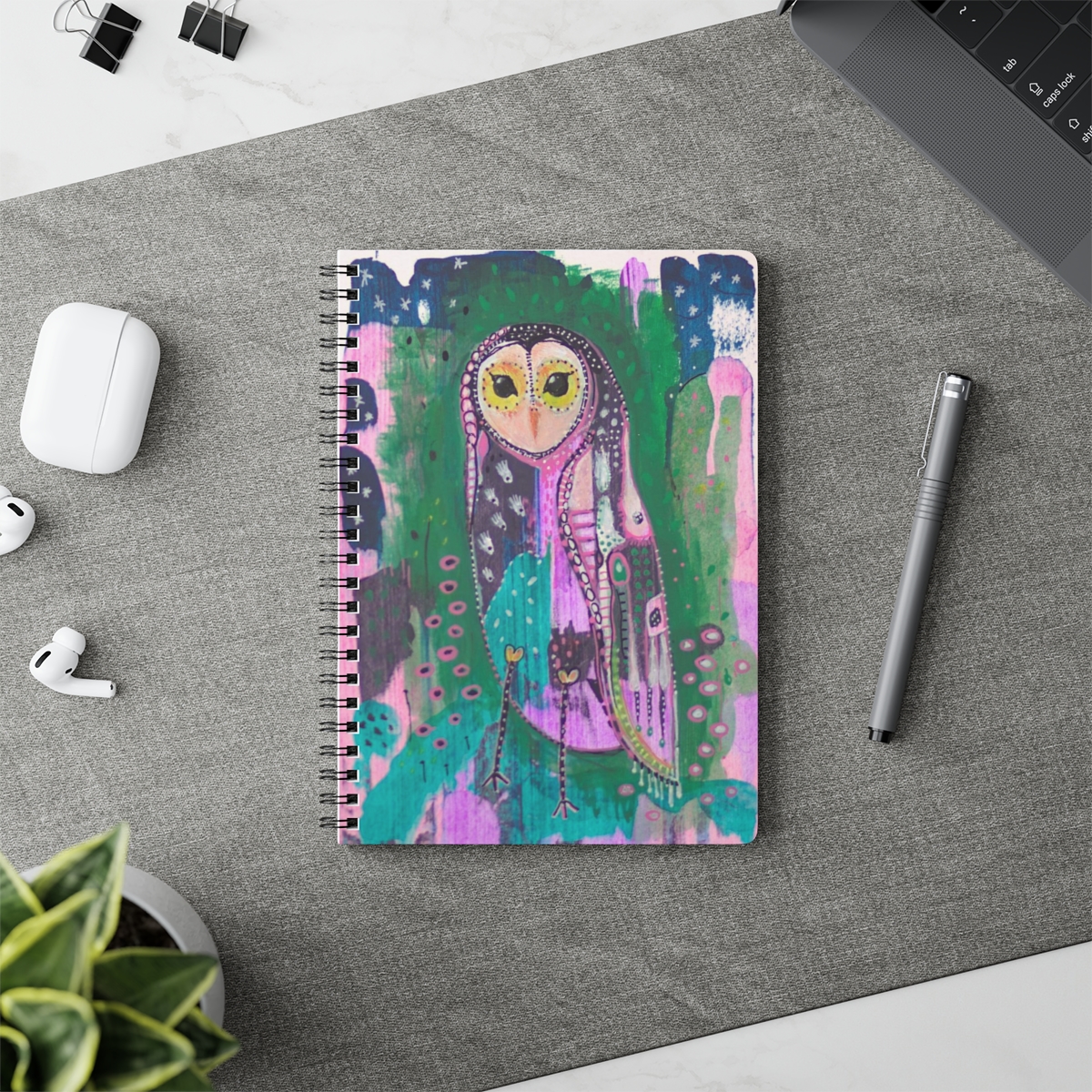 Beautiful Owl notebook in context - Owl Spirit guide is a colourful patchwork, whimsical owl based on the barn owl. She stands against an abstract background of green, pink and blue.