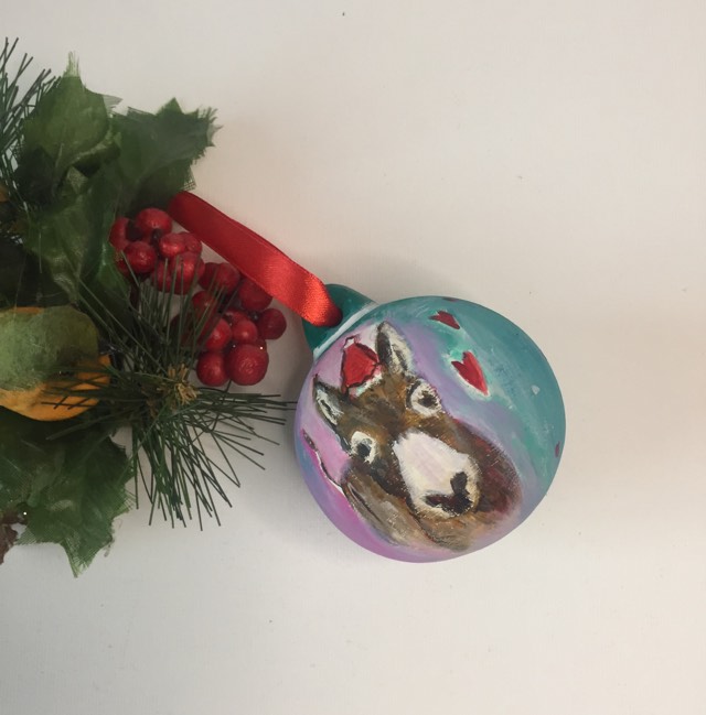 Pink and turquoise quirky keepsake Christmas bauble with red ribbon. Hand painted with a delightful donkey wearing a Christmas hat.