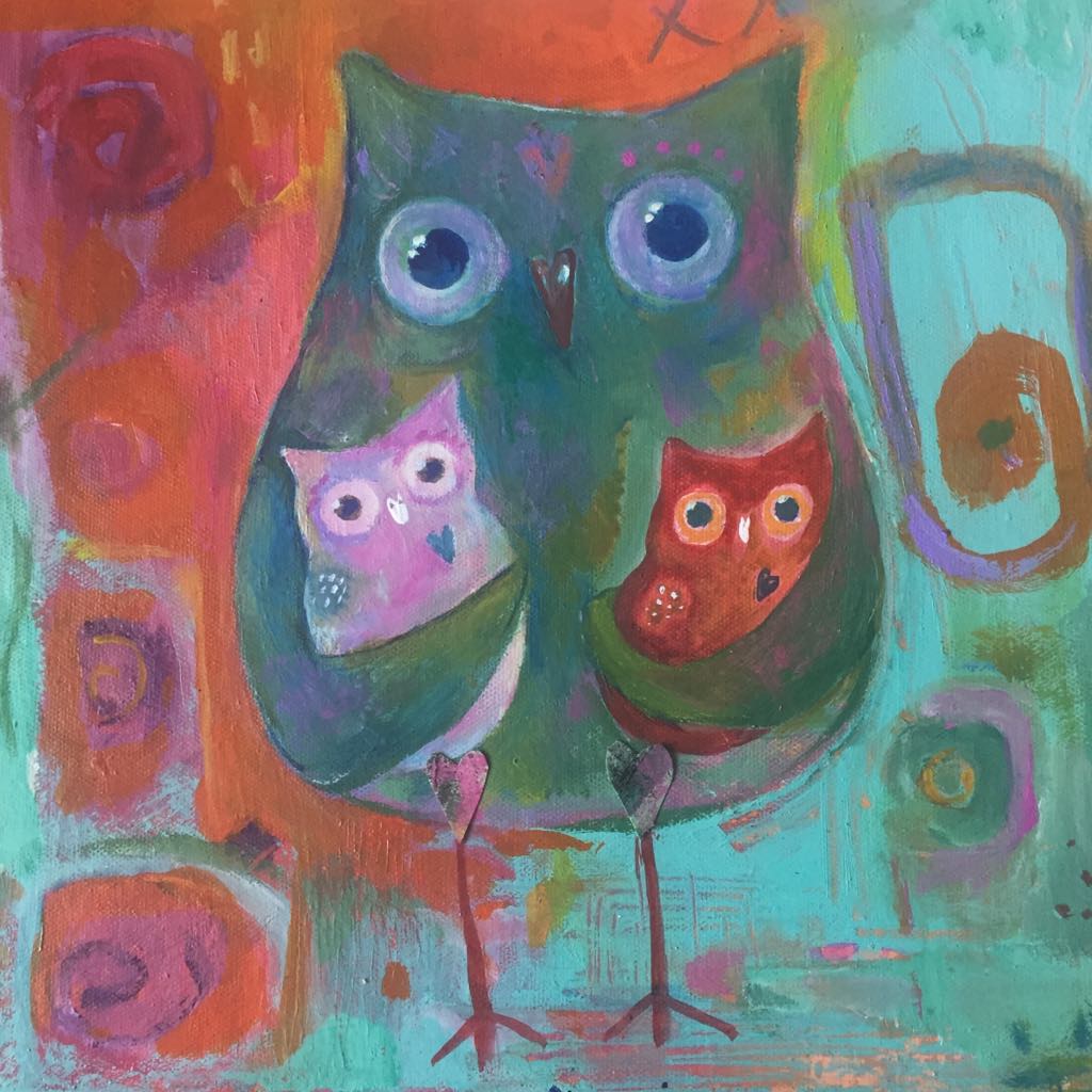 This magical owl painting shows the green mother owl standing in the centre against a bright orange and aqua abstract background. She holds her two bay owls in her wings. Spiral markings can be seen through the paint on the background.