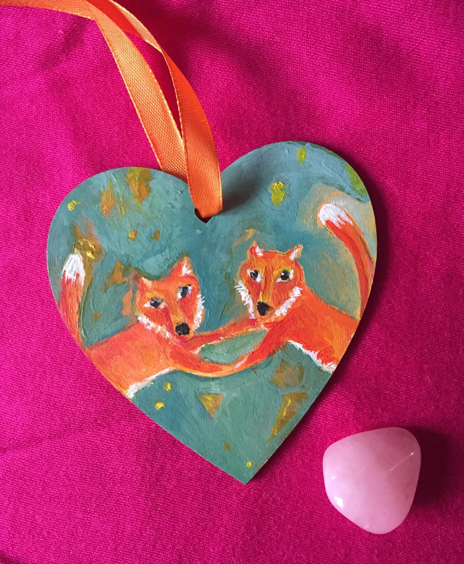 hand painted wooden heart with a pair of red foxes dancing together, holding hands on an aqua background.
